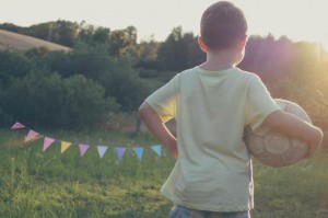 Tekst o tym, Dlaczego warto mieć pasję? Obraz przedstawia kilkuletniego chłopca, trzymającego w ręce piłkę przy blasku zachodzącego słońca.